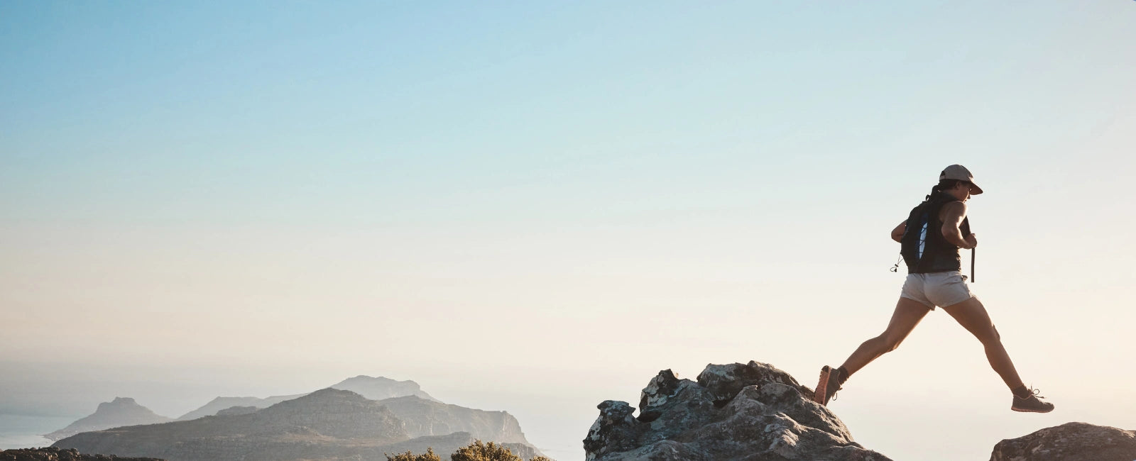 Frau springt über Felsen in der Natur – NMN von Minerva-Vita unterstützt Energie, Ausdauer und Vitalität für mehr Leistungsfähigkeit und Longevity.