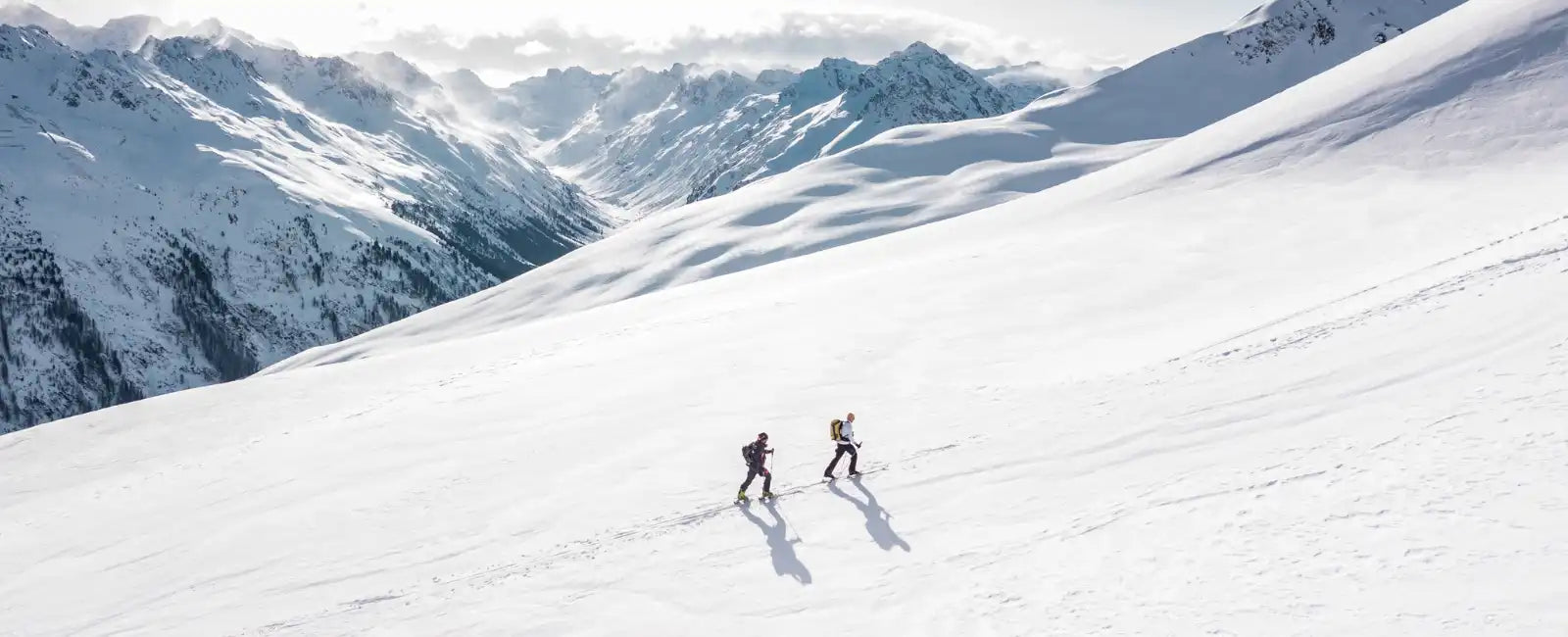 Zwei Bergsteiger im Schnee mit klarer Wintersonne – sinnbildlich für Teamwork, Energie und die Synergie von NMN, TMG und Ca-AKG im Longevity Trio von Minerva-Vita.